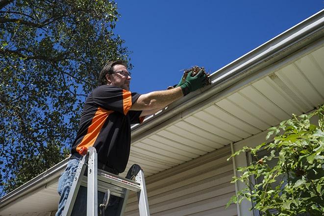 workman on a ladder repairing a broken gutter in Albert Lea MN